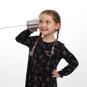 Kleines Mädchen hört an einem Dosentelefon.